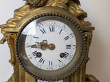 a gold clock with two birds on top of it