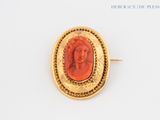 an image of a picture of a woman ' s face in a gold broocher