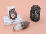 une petite horloge en argent et une petite cuillère en argent posées sur un fond rose