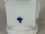 a small white vase with a blue flower on it