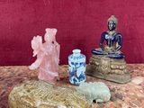 une petite statue de Bouddha assis sur un rocher, à côté d'autres objets