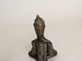 a small bronze statue of a person sitting on top of a table