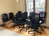 four black office chairs in a room with a large window