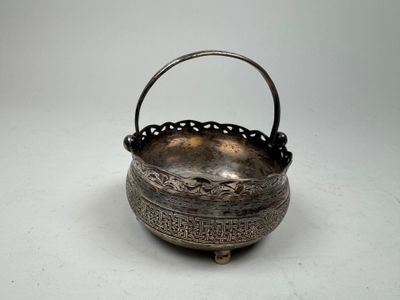 une vieille théière en argent avec une anse, posée sur une surface blanche