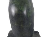 sculpture of a green owl on a black base on a white background