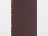 un livre marron orné de lettres dorées, posé sur une surface blanche