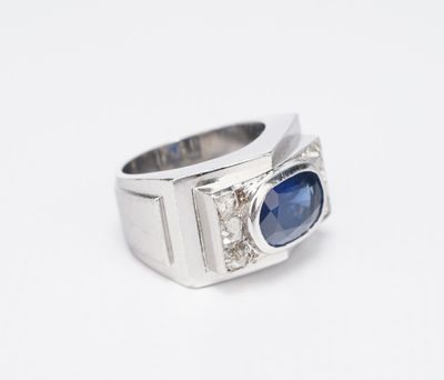 un gros plan d'une bague posée sur une surface blanche, ornée d'une pierre bleue