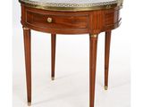 une petite table ronde avec un plateau en marbre et des finitions en laiton