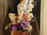 a vase of flowers sitting on a table in front of a mirror
