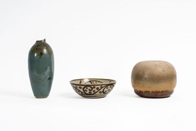 three vases and a bowl sitting next to each other on a white surface