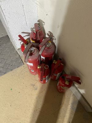 several red fire extinguisors are lined up against a wall
