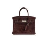 a brown leather handbag with a tassel on top of it