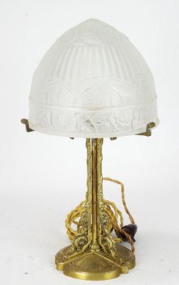 an antique brass table lamp with a glass shade and a spider on the base