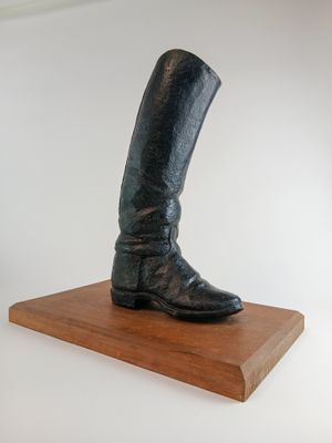 une statue représentant une paire de bottes posée sur un socle en bois