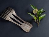 two forks and a leaf on a black surface