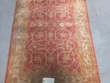 a close up of a red and beige rug on a floor