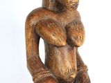 une vieille statue en bois représentant un homme assis sur une chaise