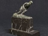 statue en bronze représentant un homme, posée sur un socle en marbre