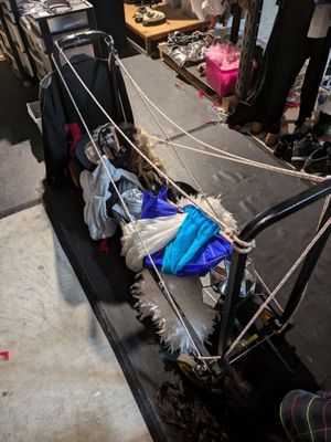 a luggage cart that has a bunch of clothes on it