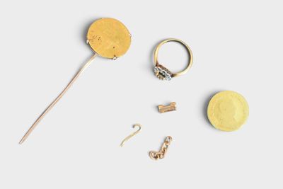 a gold ring, a gold earring, and a pair of earrings on a white surface