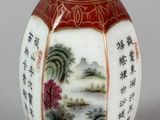 a red vase with a painting on it sitting on a table