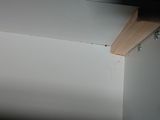 a picture of a corner of a room with a wooden shelf