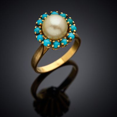 un gros plan sur une bague en or sertie d'une perle et de pierres de turquoise