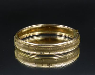 un gros plan d'un bracelet en or posé sur une surface noire