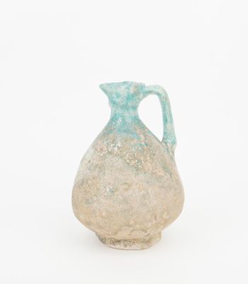 a blue and white vase with a handle on a white surface