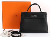 a black leather handbag next to an orange box and a pair of glasses