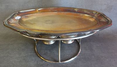 un plat ancien en argent posé sur un socle, sur une surface grise