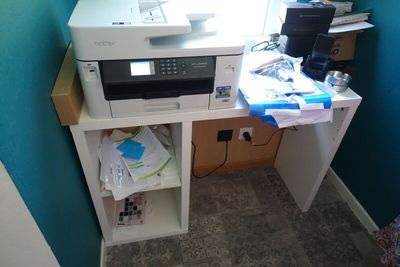 a printer sitting on top of a desk in the corner of a room
