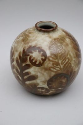 un vase brun et blanc posé sur une surface blanche