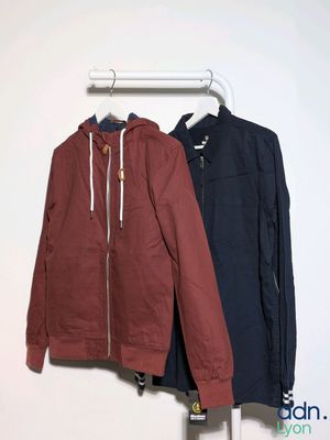 two jackets hanging on a clothes rack in a white room