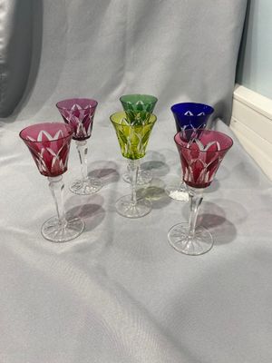 quatre verres à vin en verre de couleurs différentes posés sur une nappe blanche