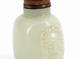 a white glass bottle with a red lid on a white surface
