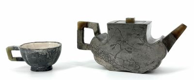 two teapots and a cup on a white surface