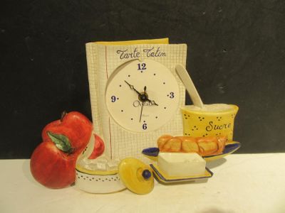 a clock that is sitting on a table next to a bowl of fruit