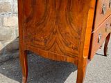 a small wooden chest of drawers sitting on the pavement