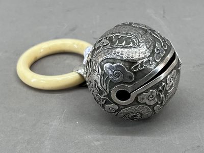 une boule en argent munie d'un anneau, posée sur une table
