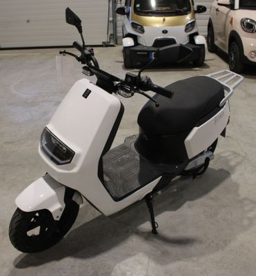 un scooter blanc garé dans un garage à côté d'autres voitures