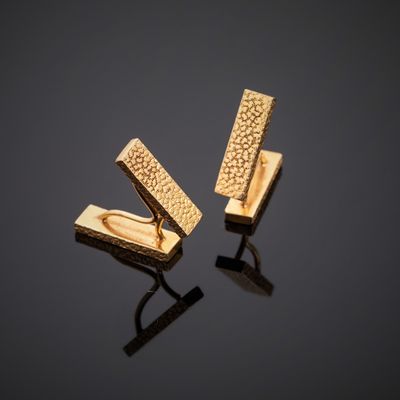 a pair of gold cufflinks on a black surface