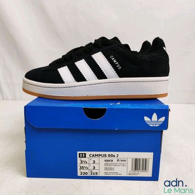 une paire de baskets noires et blanches posées sur une boîte bleue