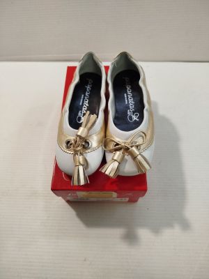 une paire de chaussures blanches et dorées ornées de nœuds, posée sur une boîte rouge