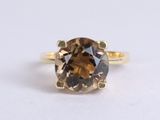un gros plan d'une bague ornée d'un diamant brun sur un fond blanc