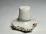 a small white candle holder with a flower design on it