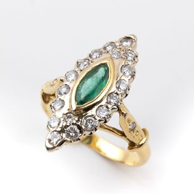 gros plan d'une bague en or avec une pierre verte et des diamants