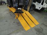 un balai posé sur un banc jaune dans un garage