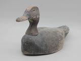 un vieux canard en bois posé sur une surface blanche