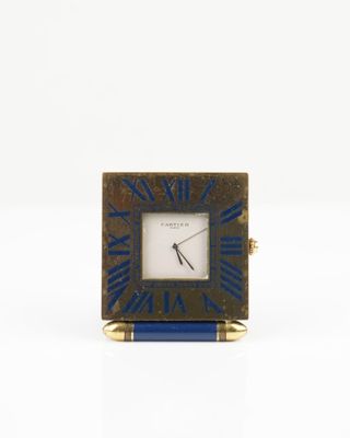 une image représentant une petite horloge carrée avec un cadre bleu et doré